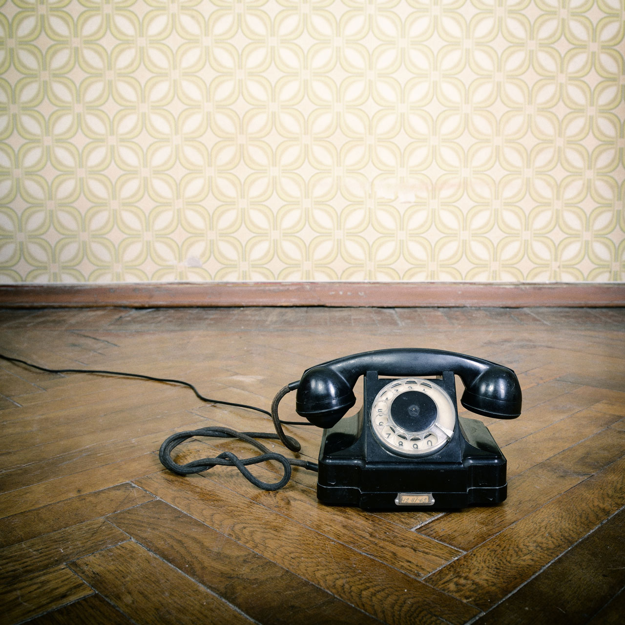 Altes schwarzes Wählscheibentelefon auf einem Parkettboden